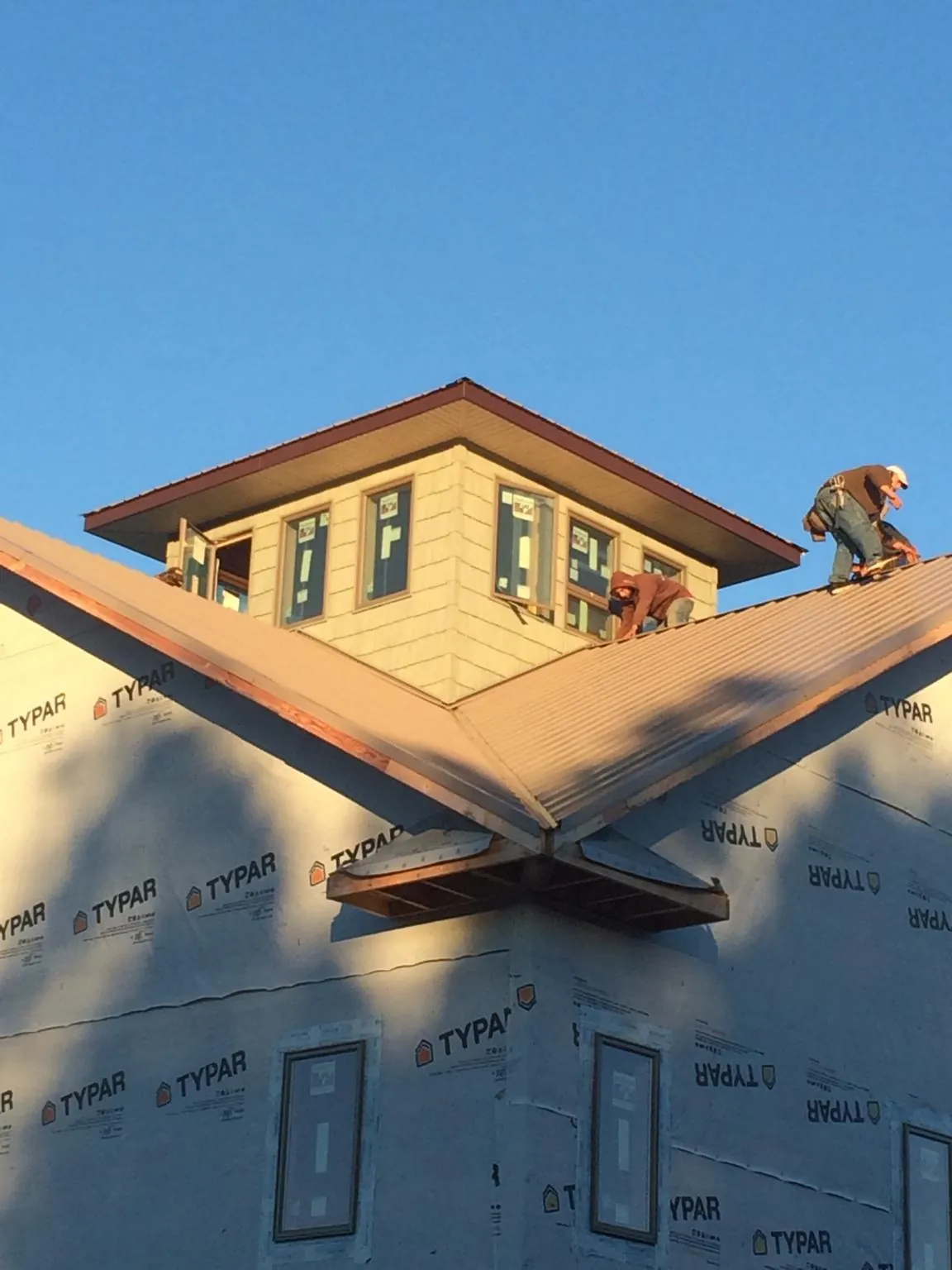 Roofers working around a rooftop cupola on a new metal roof at sunset — Roof Waterproofing in Hanover by Roofing Brothers